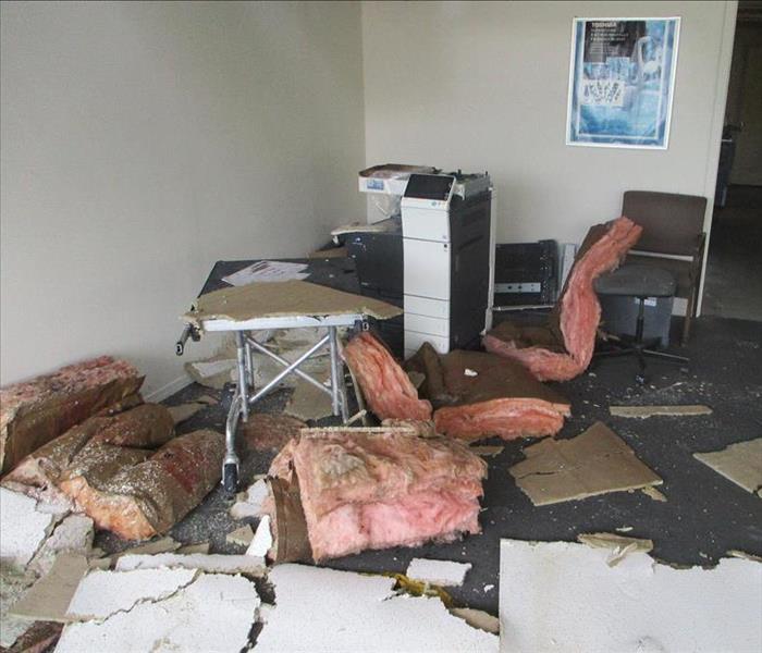 Wet insulation and ceiling drywall littered all over a floor and various furniture and copier.