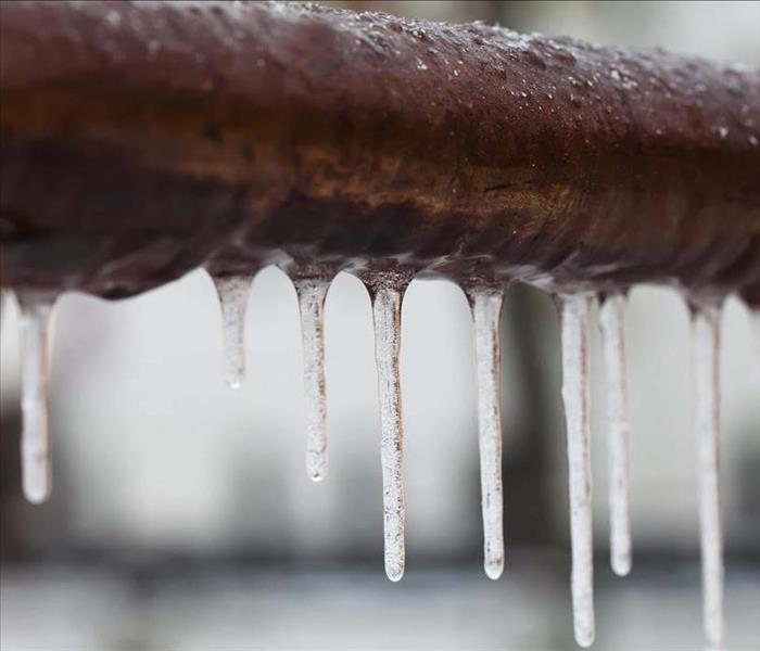 A water pipe with frozen icicles hanging from it.
