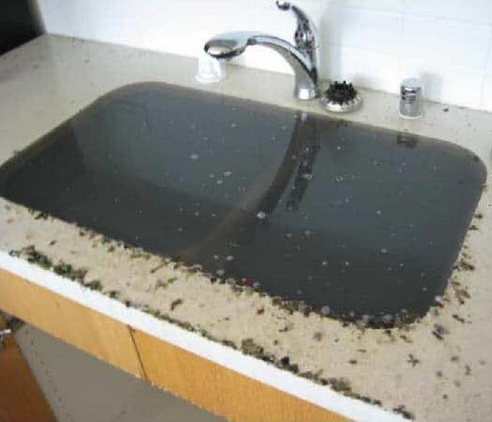 A sink overflowing with black water.